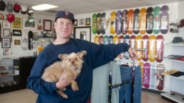 Lucas Underwood hold Ozzi the dog inside his skate shop, Dawg Pound.