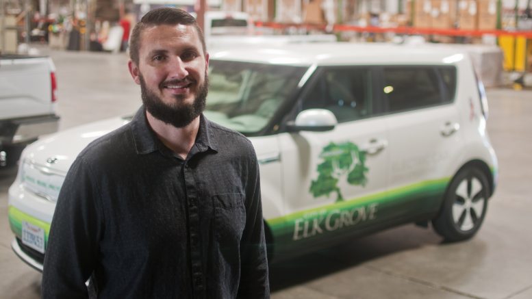 Brandon Colldeweih stands in front of a City of Elk Grove van and smiles for the camera