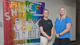 Karen Parker, left, and Cathi Johnson, right, stand in front of LGBTQ+ wall decorations