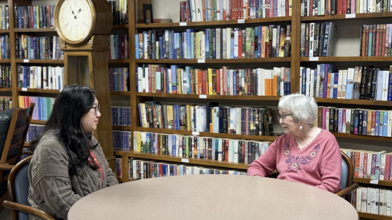 ACC PEARLS care coordinator Macy Quan sits with PEARLS participant Susan Kane at a table within a library in 2024. (Photo courtesy of ACC Senior Services)
