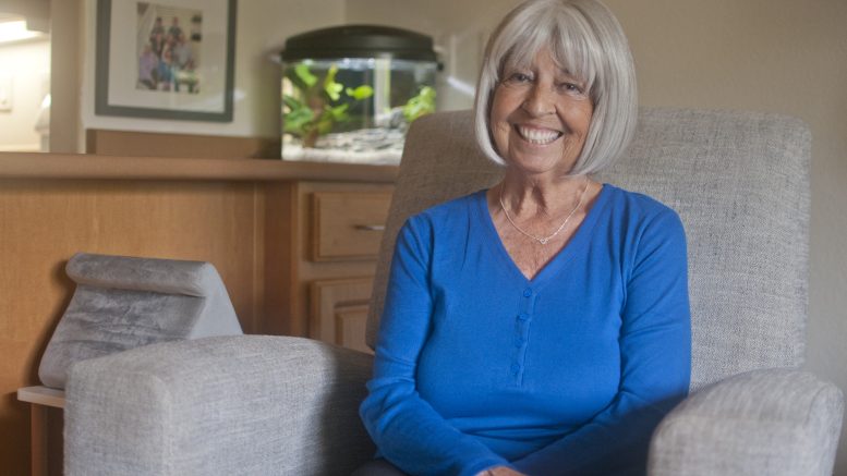 Woman smiling, while sitting in am armchair in a living room.