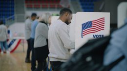 Elderly male voter with bulletin in hands comes to voting booth